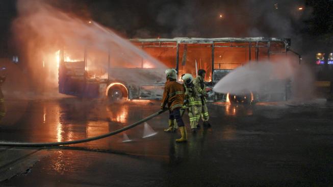 Petugas pemadam kebakaran berusaha memadamkan api yang membakar bus Transjakarta berbahan bakar gas di jalan Pos Besar, Pasar Baru, Jakarta, Senin (18/2). [ANTARA FOTO/Muhammad Adimaja]