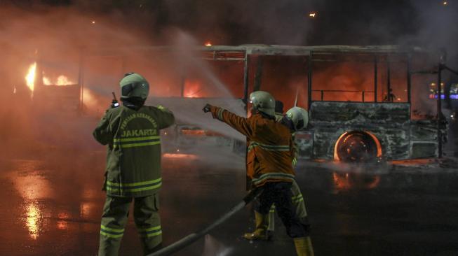 Petugas pemadam kebakaran berusaha memadamkan api yang membakar busway berbahan bakar gas di jalan Pos Besar, Pasar Baru, Jakarta, Senin (18/2). [ANTARA FOTO/Muhammad Adimaja]