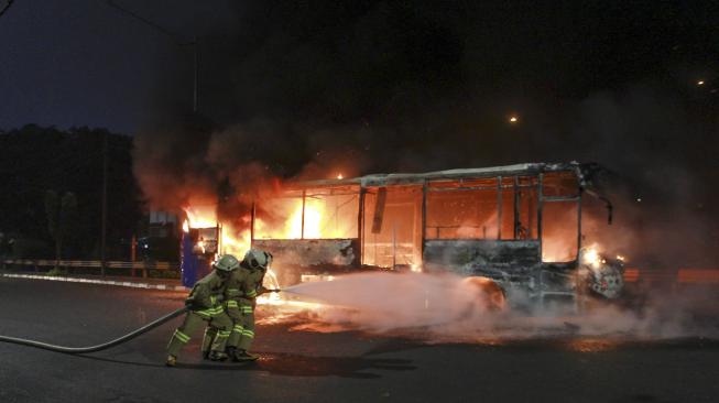 Petugas pemadam kebakaran berusaha memadamkan api yang membakar bus Transjakarta berbahan bakar gas di jalan Pos Besar, Pasar Baru, Jakarta, Senin (18/2). [ANTARA FOTO/Muhammad Adimaja]