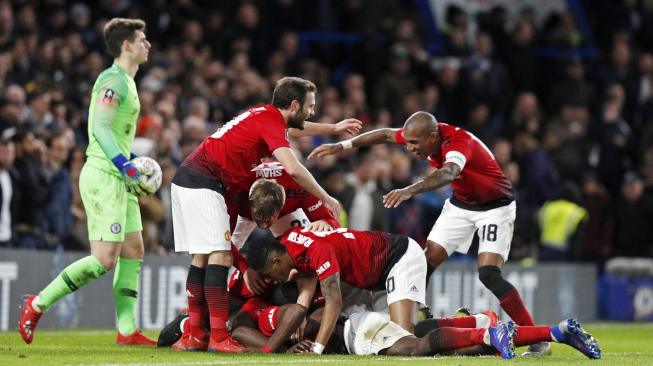 Gelandang Manchester United Paul Pogba disambut oleh rekan setimnya setelah mencetak gol kedua mereka selama pertandingan sepak bola Piala FA antara Chelsea melawan Manchester United di Stamford Bridge, London, Inggris, Selasa (19/2) dini hari WIB. [Adrian DENNIS / AFP]