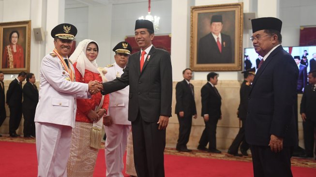 Presiden Joko Widodo (kedua kanan) didampingi Wakil Presiden Jusuf Kalla (kanan) berjabat tangan dengan Gubernur Riau yang baru dilantik Syamsuar (kiri) dan Wakil Gubernur Riau Edi Natar Nasution (ketiga kiri) di Istana Negara, Jakarta (20/2). [ANTARA FOTO/Akbar Nugroho Gumay]