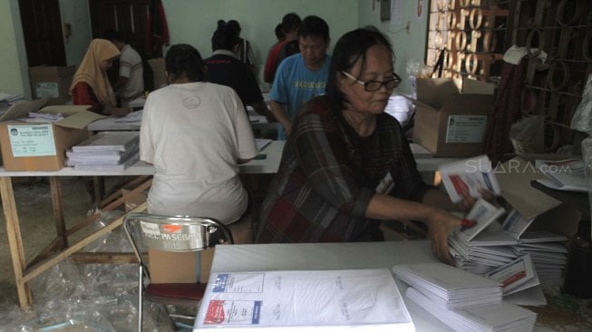 Sejumlah petugas melipat surat suara pemilu di Kantor KPU Jakarta Pusat, Kamis (21/2). [Suara.com/Fakhri Hermansyah]