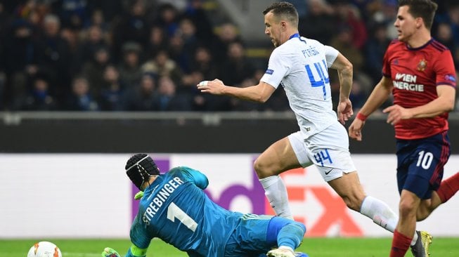 Gelandang Inter Milan Ivan Perisic mengungguli kiper Rapid Vienna Richard Strebinger dan pemain tengah Rapid Vienna  selama pertandingan leg kedua babak 32 besar Liga Europa antara Inter Milan melawan Rapid Vienna di Stadion Guiseppe Meazza,Milan, Italia, Jumat (22/2) dini hari WIB. [Miguel MEDINA / AFP]