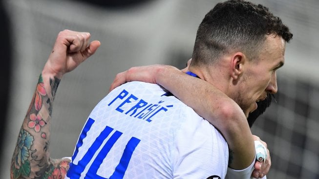 Gelandang Inter Milan, Ivan Perisic, merangkul gelandang Inter Milan Matteo Politano setelah ia mencetak gol selama pertandingan leg kedua babak 32 besar Liga Europa antara Inter Milan melawan Rapid Vienna di Stadion Guiseppe Meazza, Milan, Italia, Jumat (22/2) dini hari WIB. [Miguel MEDINA / AFP]