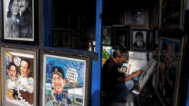 Pelukis sedang berada di kios Sentra Lukisan di kawasan Pasar Baru, Jakarta, Jumat (22/2). [Suara.com/Muhaimin A Untung]