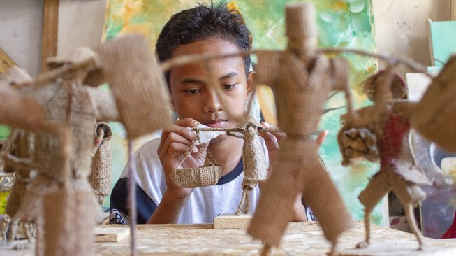 Perajin menyelesaikan pembuatan kerajinan boneka tani berbahan karung goni di Saung Atap Langit, Kampung Tangkolak, Cilamaya Wetan, Karawang, Jawa Barat, Sabtu (23/2).  [ANTARA FOTO/M Ibnu Chazar]