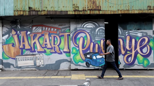 Warga melintas di depan mural kawasan Berok, Penjaringan, Jakarta Utara, Minggu (24/2). [Suara.com/Muhaimin A Untung]