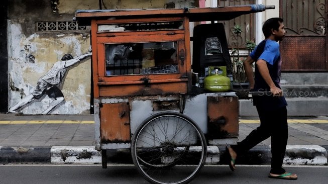 Warga melintas di depan mural kawasan Berok, Penjaringan, Jakarta Utara, Minggu (24/2). [Suara.com/Muhaimin A Untung]