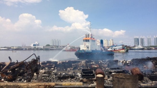 Pasca kebakaran kapal nelayan di Pelabuhan Muara Baru, Penjaringan, Jakarta Utara masih mengeluarkan asap hingga hari ini. (Suara.com/Yasir)