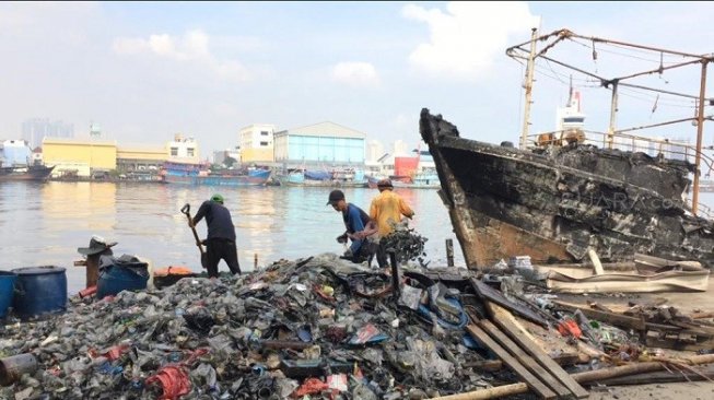 Petugas sedang mengangkut puing-puing sisa kebakaran di Pelabuhan Muara Baru. (Suara.com/M Yasir)