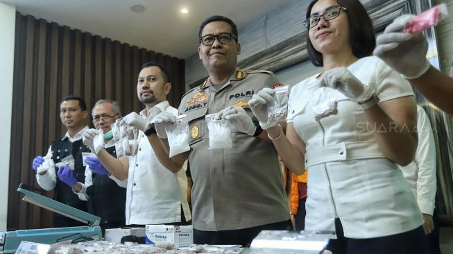 Kabid Humas Polda Metro Jaya Kombes Argo Yuwono (ketiga kanan) bersama dengan Kasubdit 1 Ditresnarkoba Polda Metro Jaya AKBP Jean Calvin Simanjuntak  (ketiga kiri) menunukan barang bukti narkotika jenis baru berbentuk 'Diamond' saat rilis di Polda Metro Jaya, Jakarta, Senin (25/2). [Suara.com/Muhaimin A Untung]