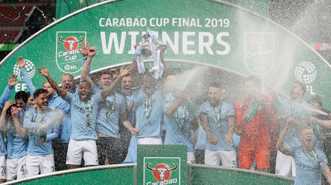 Bek Manchester City Vincent Kompany mengangkat trofi Piala Liga Inggris saat merayakan kemenangan mereka dalam pertandingan sepak bola final Piala Liga Inggris antara Manchester City melawan Chelsea di Stadion Wembley, London, Inggris, Minggu (24/2).[Adrian DENNIS / AFP]