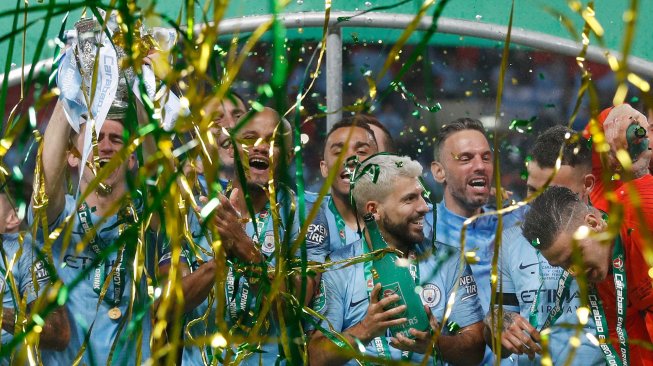 Bek Manchester City Vincent Kompany mengangkat trofi Piala Liga Inggris saat merayakan kemenangan mereka dalam pertandingan sepak bola final Piala Liga Inggris antara Manchester City melawan Chelsea di Stadion Wembley, London, Inggris, Minggu (24/2).[Adrian DENNIS / AFP]