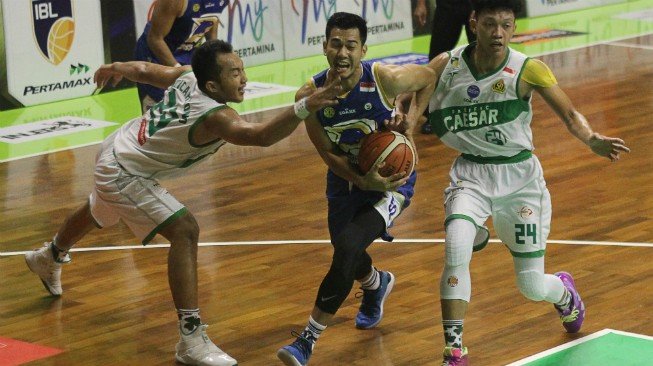 Pebasket Prawira Bandung Surliyadin (tengah) mencoba melewati hadangan pebasket Pacific Caesar Surabaya Muhammad Hardian Wicaksono (kiri) dan Indra Muhammad saat pertandingan IBL 2018-2019 seri Surabaya di GOR Pasific, Surabaya, Jawa Timur, Sabtu (2/2/2019). [Antara/Moch Asim]