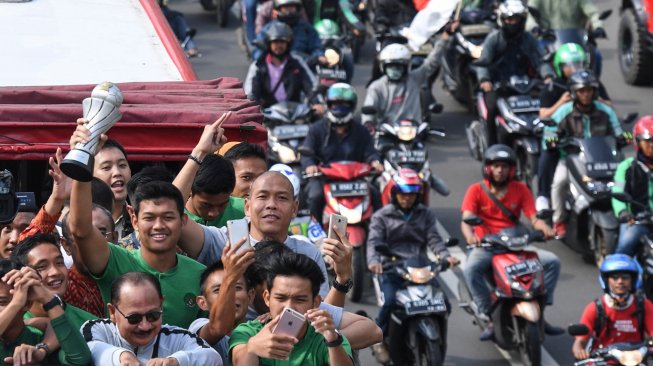 Pemain dan ofisial Timnas U-22 Indonesia menaiki bus tingkat ketika mengikuti konvoi menuju Istana Negara saat melintas di Jalan Sudirman, Jakarta, Kamis (28/2). [ANTARA FOTO/Hafidz Mubarak]
