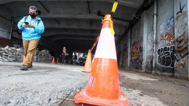 Warga melintas di samping proyek pedestrian Jalan Kendal di bawah Flyover Jalan Sudirman, Dukuh Atas, Jakarta, Selasa (5/3). [Suara.com/Muhaimin A Untung]