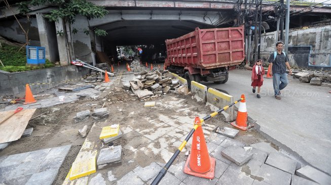 Warga melintas di samping proyek pedestrian Jalan Kendal di bawah Flyover Jalan Sudirman, Dukuh Atas, Jakarta, Selasa (5/3). [Suara.com/Muhaimin A Untung]