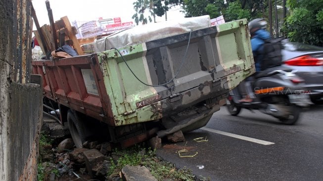 Truk pengangkut batu granit amblas masuk ke dalam lubang saluran air sehingga menutupi sebagian badan jalan di Jalan Pejaten Barat, Pasar Minggu, Jakarta Selatan, Selasa (5/3). [Suara.com/Arief Hermawan P]