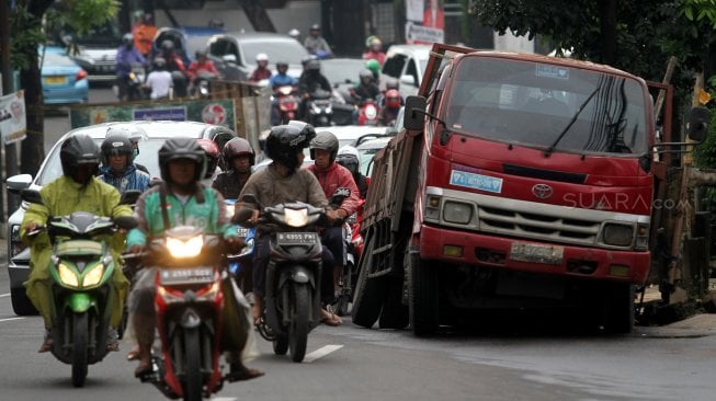 Truk pengangkut batu granit amblas masuk ke dalam lubang saluran air sehingga menutupi sebagian badan jalan di Jalan Pejaten Barat, Pasar Minggu, Jakarta Selatan, Selasa (5/3). [Suara.com/Arief Hermawan P]