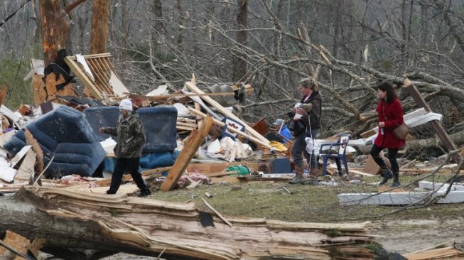 Warga Lee County, Alabama melintasi reruntuhan rumah dan pohon yang tumbang akibat diterjang badai pada Minggu (3/3/2019). (Foto: AFP)