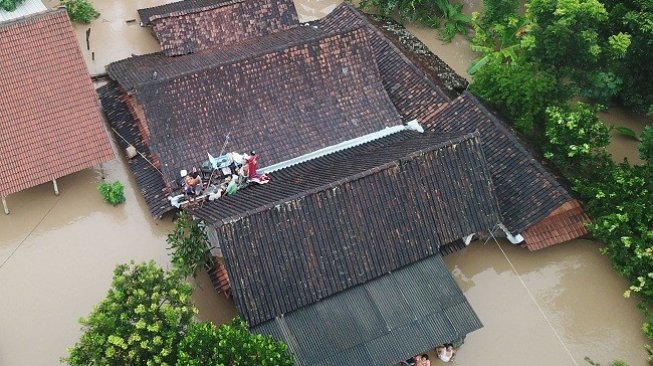 Sejumlah warga menyelamatkan diri di atas atap rumah saat terjadi banjir di Desa Purworejo, Pilangkenceng, Kabupaten Madiun, Jawa Timur, Rabu (6/3/2019). ANTARA FOTO/Dio Pratama