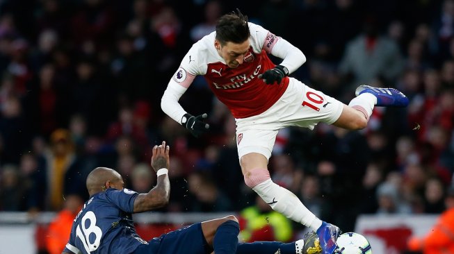 Gelandang Manchester United Ashley Young menghadang pemain tengah Arsenal asal Mesut Ozil pertandingan sepak bola Liga Primer Inggris antara Arsenal melawan Manchester United di Stadion Emirates, London, Inggris, Minggu (10/3). [Ian KINGTON / IKIMAGES / AFP]
