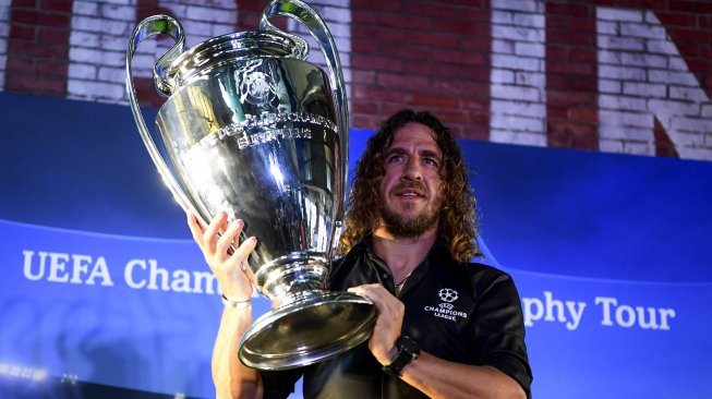 Pesepak bola legenda FC Barcelona Carles Puyol berpose di dekat trofi Liga Champions saat mengikuti UEFA Champions League Thropy Tour di Jakarta, Senin (11/3). [ANTARA FOTO/Hafidz Mubarak A]