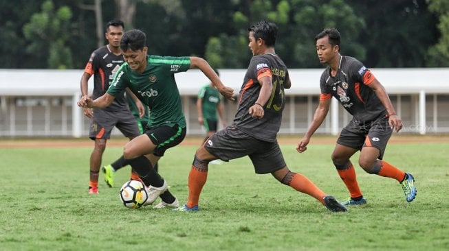 Pemain Timnas Indonesia U-23 berebut bola dengan pemain Semen Padang dalam laga uji coba di Stadion Madya, Kompleks Gelora Bung Karno, Senayan, Jakarta, Selasa (12/3). [Suara.com/Muhaimin A Untung]