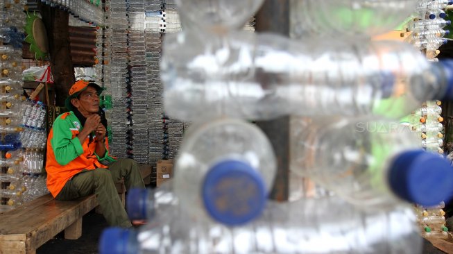 Petugas Unit Pengelola Kegiatan (UPK) Badan Air Dinas Lingkungan Hidup DKI Jakarta menunjukkan botol plastik yang disusun membentuk bangunan posko di kawasan Ciracas, Jakarta Timur, Rabu (13/3). [Suara.com/Arief Hermawan P]