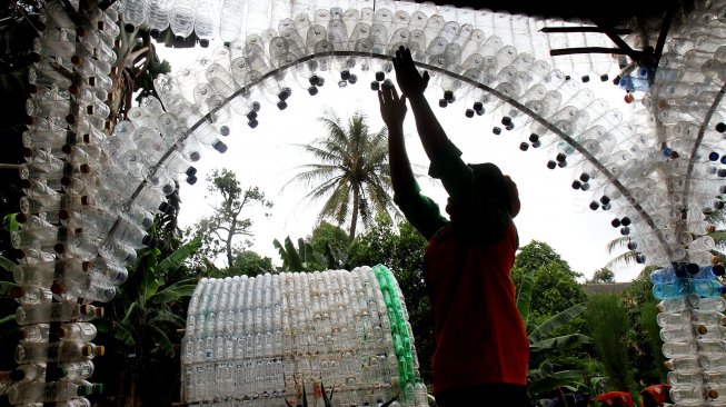 Petugas Unit Pengelola Kegiatan (UPK) Badan Air Dinas Lingkungan Hidup DKI Jakarta menunjukkan botol plastik yang disusun membentuk bangunan posko di kawasan Ciracas, Jakarta Timur, Rabu (13/3). [Suara.com/Arief Hermawan P]