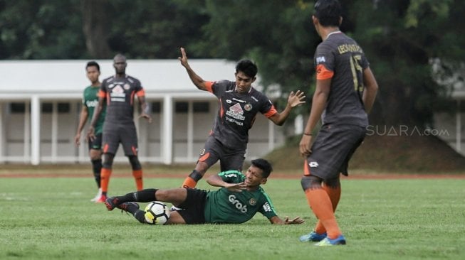 Pemain Timnas Indonesia U-23 berebut bola dengan pemain Semen Padang dalam laga uji coba di Stadion Madya, Kompleks Gelora Bung Karno, Senayan, Jakarta, Selasa (12/3). [Suara.com/Muhaimin A Untung]