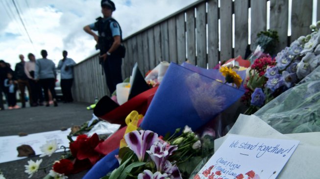 Petugas kepolisian berjaga didekat bunga yang diletakkan warga di depan Masjid Wellington, Kilbirnie, Wellington, Selandia Baru, Sabtu (16/3). ANTARA FOTO/Ramadian Bachtiar