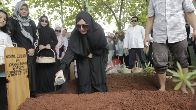 Eddies Adelia menyirami air kembang di pemakaman sang ayah. (Wahyu Tri Laksono/Suara.com)