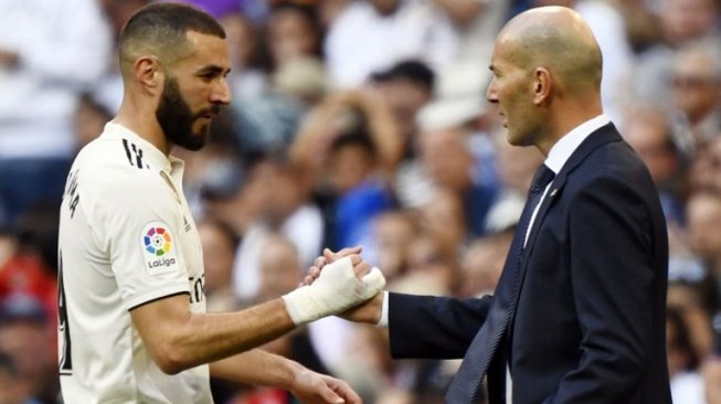 Pelatih baru Real Madrid, Zinedine Zidane (kanan) menyalami striker Karim Benzema pada laga lanjutan Liga Spanyol 2018/2019 kontra Celta Vigo di Santiago Bernabeu, Minggu (17/3/2019) dini hari WIB. [GABRIEL BOUYS / AFP]