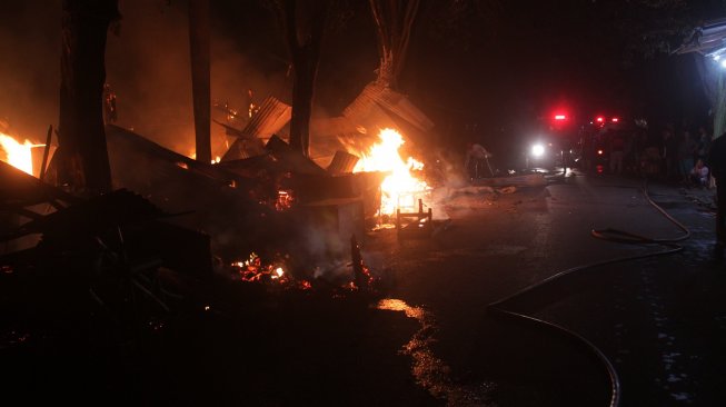 Petugas pemadam kebakaran menyiram api yang membakar lapak semi permanen di Pasar Legi, Jombang, Jawa Timur, Senin (18/3). [ANTARA FOTO/Syaiful Arif]