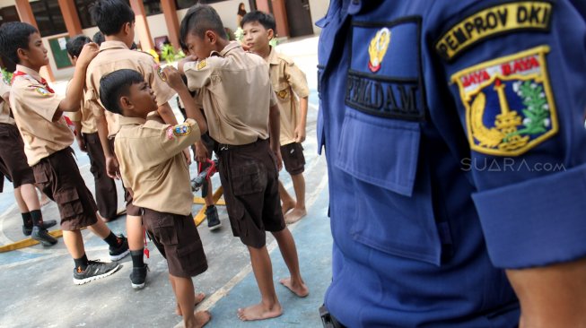 Petugas Suku Dinas Pemadam Kebakaran (Damkar) Jakarta Selatan bersama sejumlah siswa melakukan simulasi pemadaman kebakaran di SDN Kebagusan 01 Pagi, Rabu (20/3). [Suara.com/Arief Hermawan P]