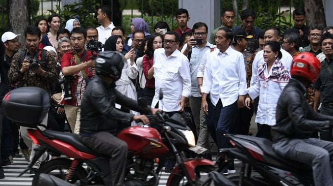 Presiden Joko Widodo bersama Ibu Negara Iriana Joko Widodo melintasi jalan menuju Halte Monas di Jakarta, Kamis (21/3). ANTARA FOTO / Puspa Perwitasari