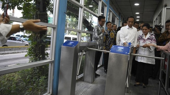 Presiden Joko Widodo (tengah) bersama Ibu Negara Iriana Joko Widodo (kanan) menyiapkan menaiki bus Transjakarta menuju Stasiun MRT Bundaran Hotel Indonesia di Jakarta, Kamis (21/3). ANTARA FOTO / Puspa Perwitasari