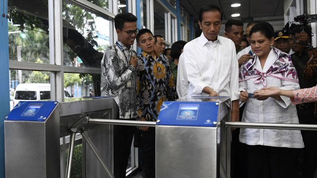 Presiden Joko Widodo (tengah) bersama Ibu Negara Iriana Joko Widodo (kanan) menyiapkan menaiki bus Transjakarta menuju Stasiun MRT Bundaran Hotel Indonesia di Jakarta, Kamis (21/3). ANTARA FOTO / Puspa Perwitasari