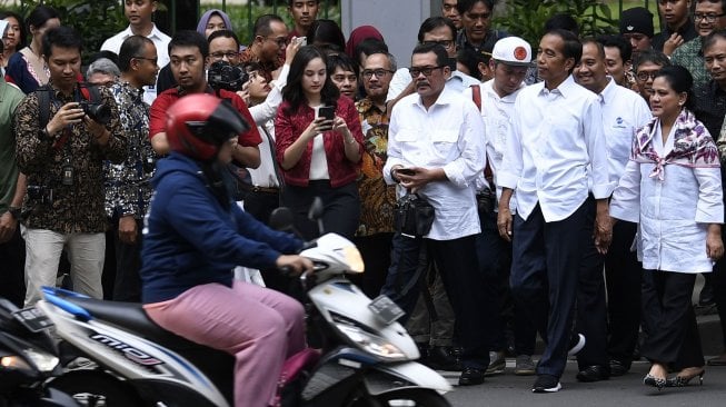 Presiden Joko Widodo bersama Ibu Negara Iriana Joko Widodo melintasi jalan menuju Halte Monas di Jakarta, Kamis (21/3). ANTARA FOTO / Puspa Perwitasari