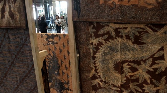 Pengunjung memperhatikan beragam produk batik dan tenun di sejumlah stan pada pameran Adiwastra di JCC, Jakarta, Sabtu (23/3).  [Suara.com/Arief Hermawan P]