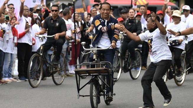 Calon Presiden petahana Joko Widodo (tengah) bersama istri Iriana Joko Widodo (kanan) bersepeda onthel menuju lokasi Deklarasi Alumni Jogja Satukan Indonesia di Stadion Kridosono, Yogyakarta, Sabtu (23/3).  [ANTARA FOTO/Puspa Perwitasari]