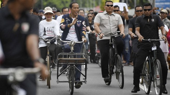 Calon Presiden petahana Joko Widodo (tengah) bersama istri Iriana Joko Widodo (kanan) bersepeda onthel menuju lokasi Deklarasi Alumni Jogja Satukan Indonesia di Stadion Kridosono, Yogyakarta, Sabtu (23/3).  [ANTARA FOTO/Puspa Perwitasari]