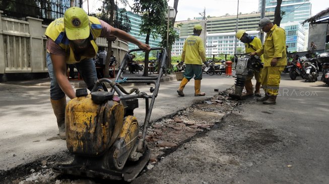 Pekerja melakukan pembongkaran beton pembatas jalan di Jalan M Yamin bagian sisi barat, Menteng, Jakarta, Senin (25/3).[Suara.com/Muhaimin A Untung]