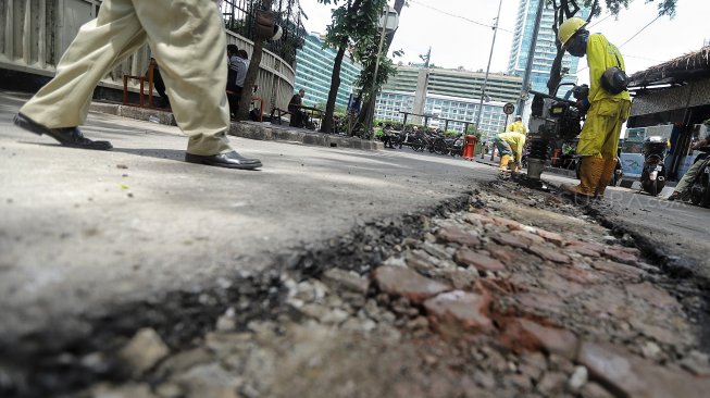 Pekerja melakukan pembongkaran beton pembatas jalan di Jalan M Yamin bagian sisi barat, Menteng, Jakarta, Senin (25/3).[Suara.com/Muhaimin A Untung]