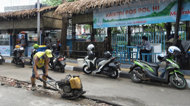 Pekerja melakukan pembongkaran beton pembatas jalan di Jalan M Yamin bagian sisi barat, Menteng, Jakarta, Senin (25/3).[Suara.com/Muhaimin A Untung]