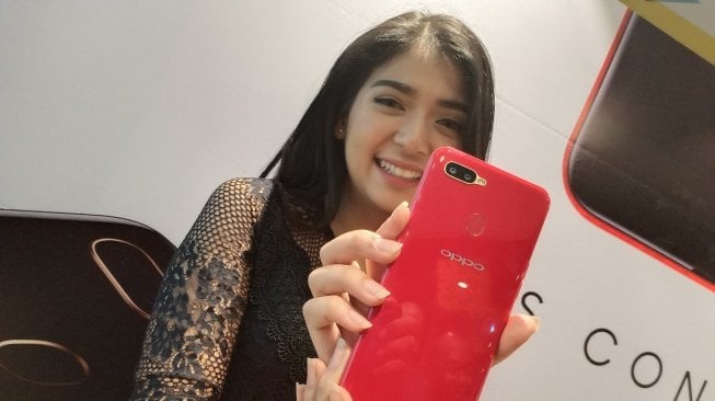 Seorang model sedang menunjukkan ponsel Oppo A5s di Jakarta, Senin (25/3/2019). [Suara.com/Tivan Rahmat]