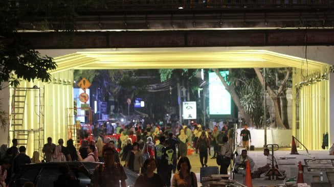 Warga melintasi terowongan yang dihiasi lampu warna-warni di Jalan Kendal, sekitar Stasiun Sudirman, Jakarta, Selasa (26/3). [Suara.com/Arief Hermawan P]