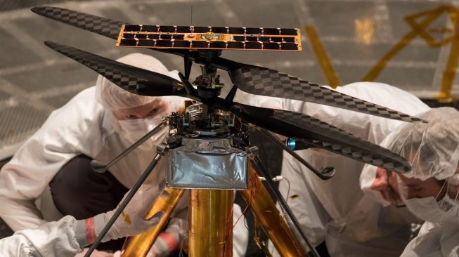 Para insinyur NASA tengah memeriksa sebuah helikopter model di dalam tabung kedap udara yang berfungsi sebagai simulator antariksa di laboratorium Jet Propulsion, Pasadena, California, AS pada 1 Februari 2019. NASA berencana menerbangkan helikoter pertama di Mars pada 2021. [Courtesy NASA/JPL-Caltech]