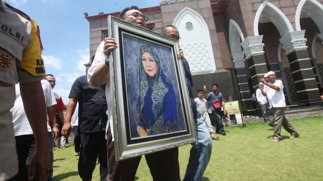 Anggota keluarga membawa foto almarhumah Dian Djuriah Rais di Masjid Kubah Emas Cinere Depok, Jabar, Jumat (29/3).  [ANTARA FOTO/Kahfie Kamaru]